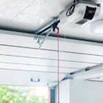 A modern garage interior contains a mounted garage door opener with a red emergency cord and metal track.