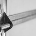 A close-up view of the interior of a residential garage door, highlighting a shiny metal bracket and screws.