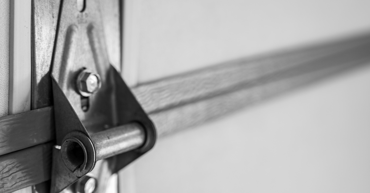 A close-up view of the interior of a residential garage door, highlighting a shiny metal bracket and screws.