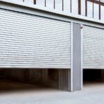 Two partially open silver rolling steel doors on the exterior of a commercial warehouse, revealing spacious storage areas inside.